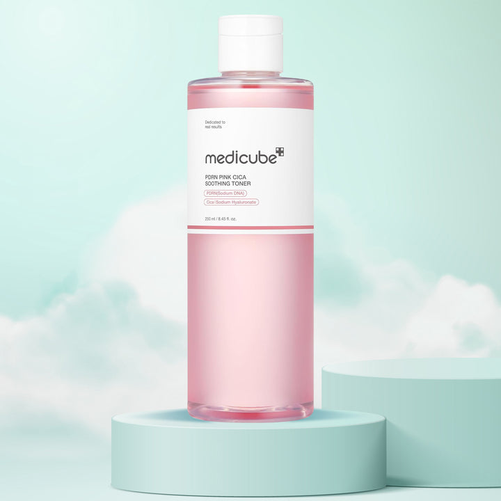 Pink bottle of Medicube toner on a light blue platform with a light blue background