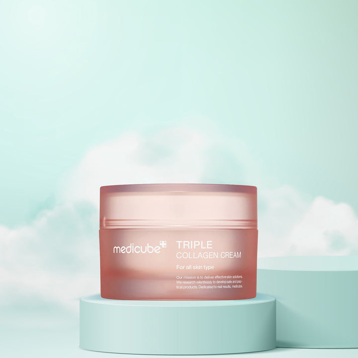 A jar of Medicube Triple Collagen Cream placed on a pedestal against a sky with clouds, indicating a skincare product.