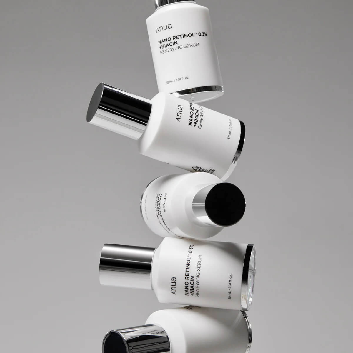 Stack of skincare bottles with visible branding on a gray background