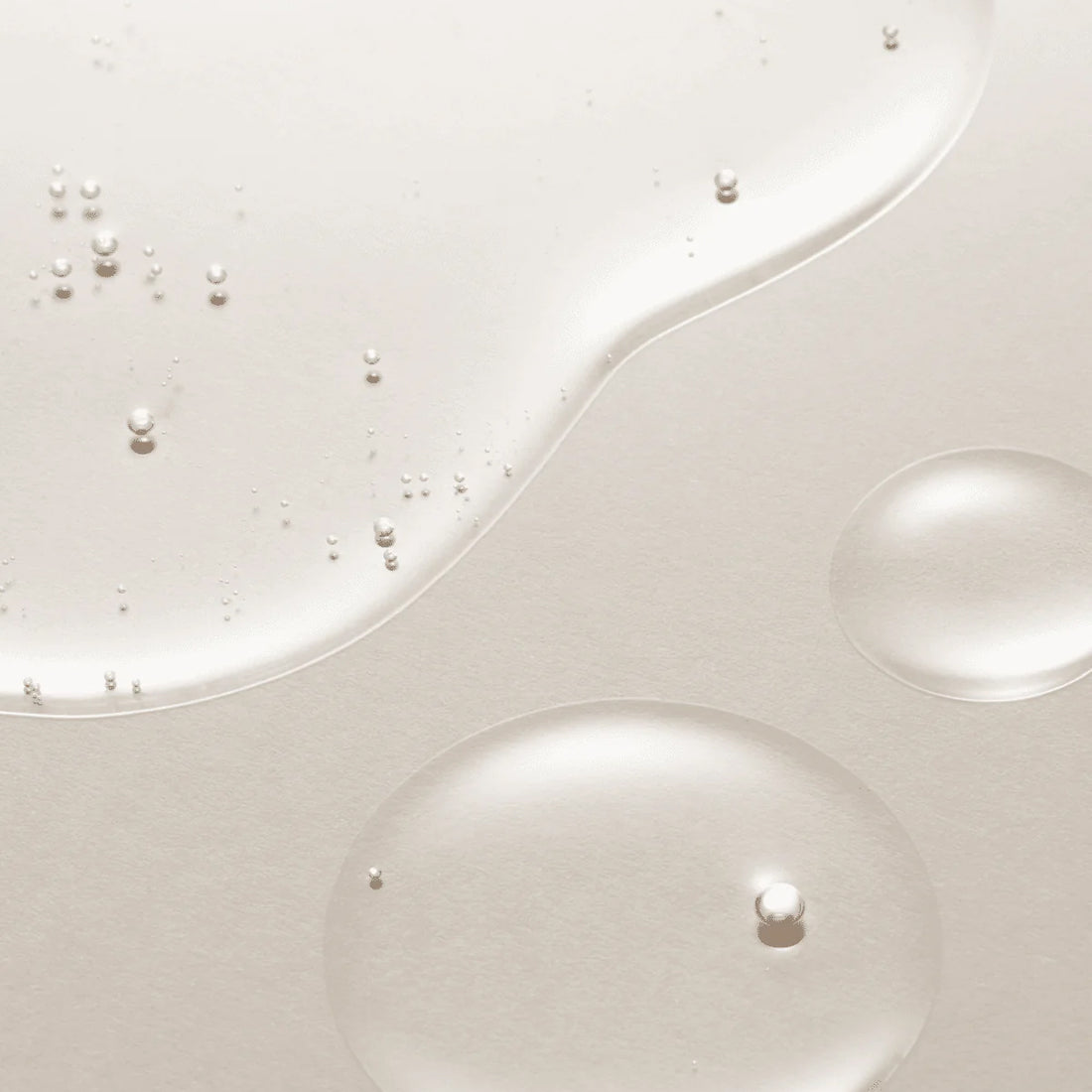 Close-up of white liquid with pearl-like beads on a light gray background
