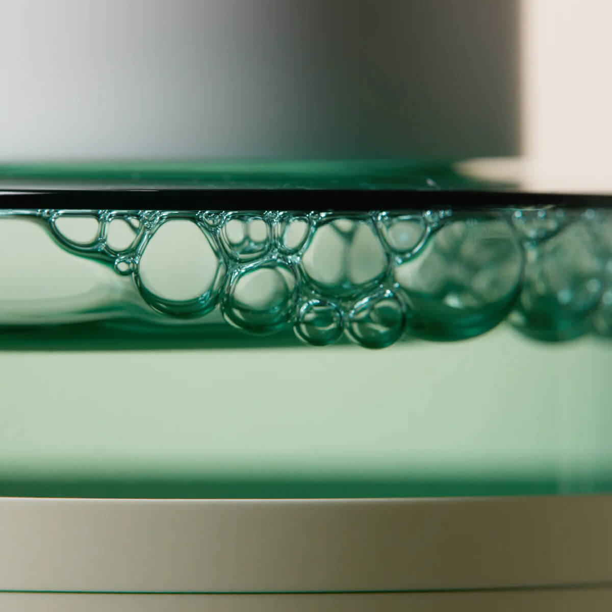 Close-up of a green glass object with bubble patterns on a reflective surface.