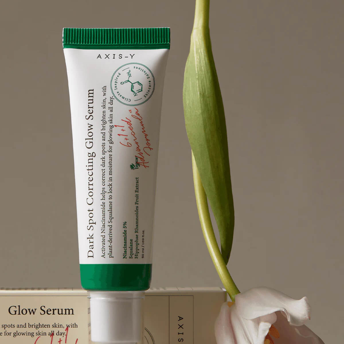 Tube of AXIS-Y Dark Spot Correcting Glow Serum with a plant in the background