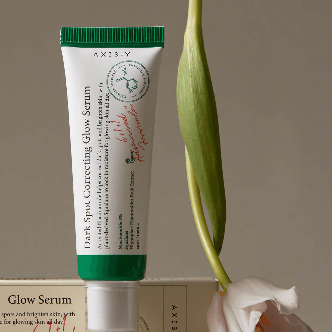 Tube of AXIS-Y Dark Spot Correcting Glow Serum with a plant in the background