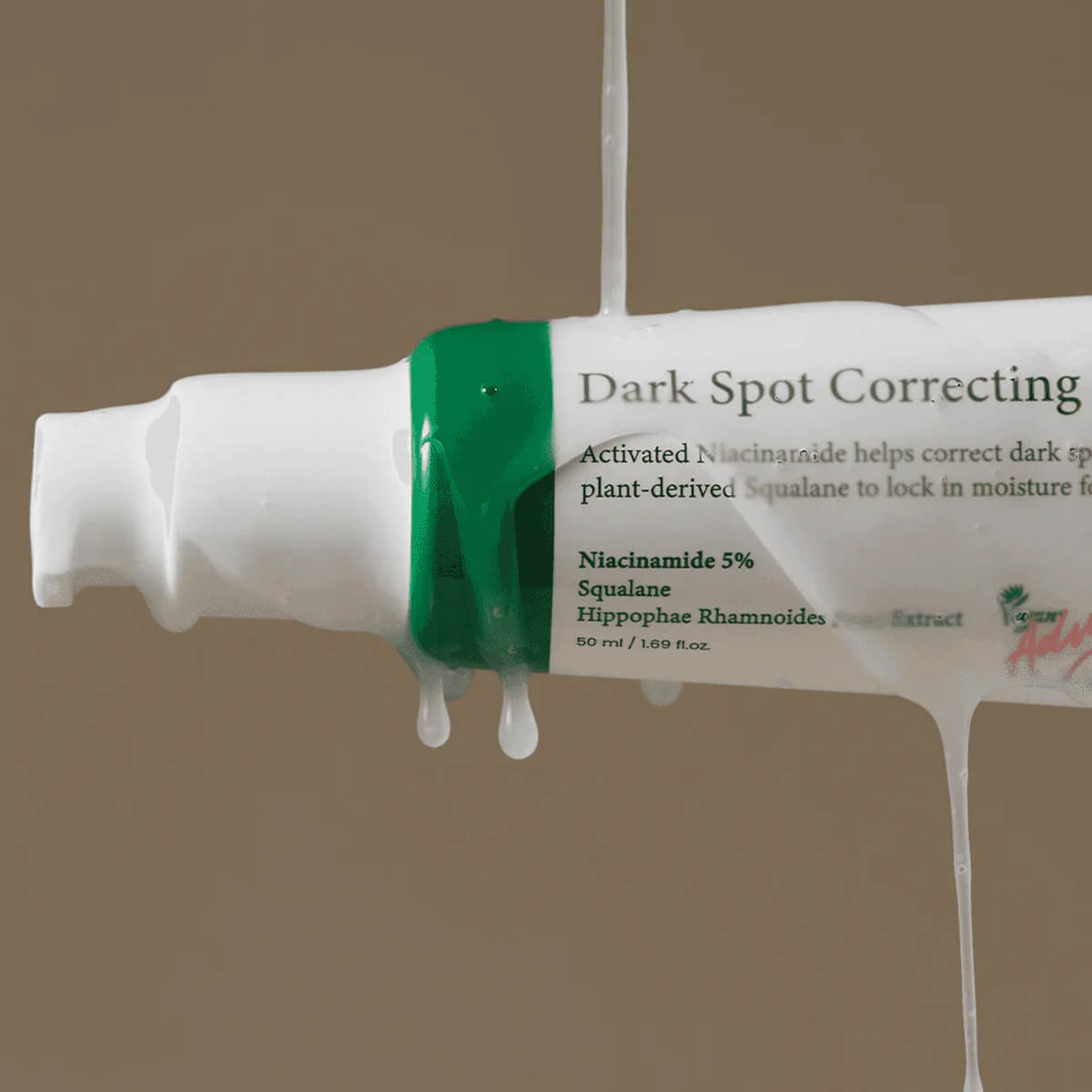 Tube of dark spot correcting cream with visible label on a beige background