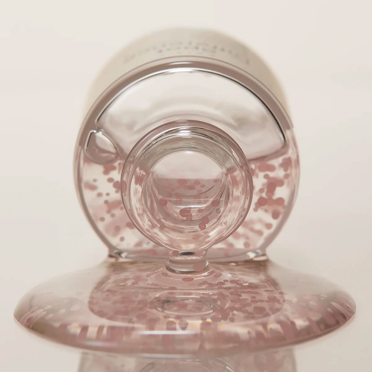 Clear glass with pink speckled base on a white background