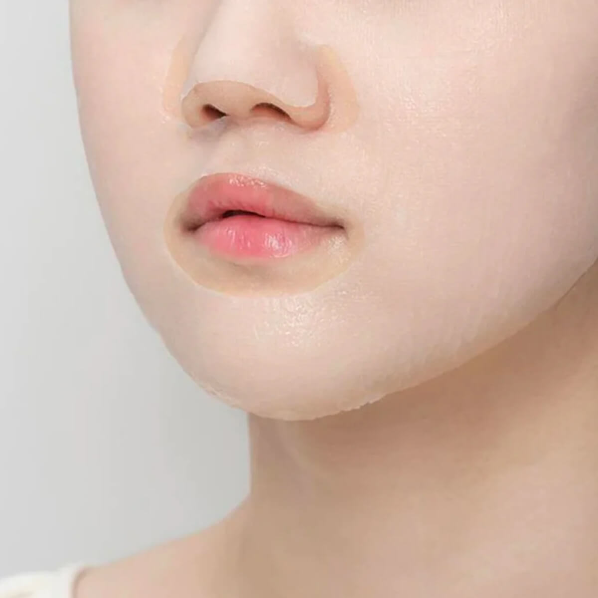 Close-up of a person's face with a neutral expression on a plain background