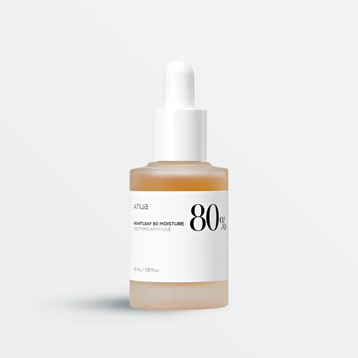 A clear glass dropper bottle of Anua Heartleaf 80% Soothing Ampoule with a white label and cap, containing a yellow-toned liquid.