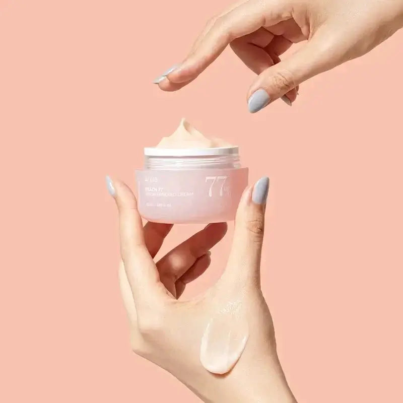 Hand holding a pink jar of cream with a beige background