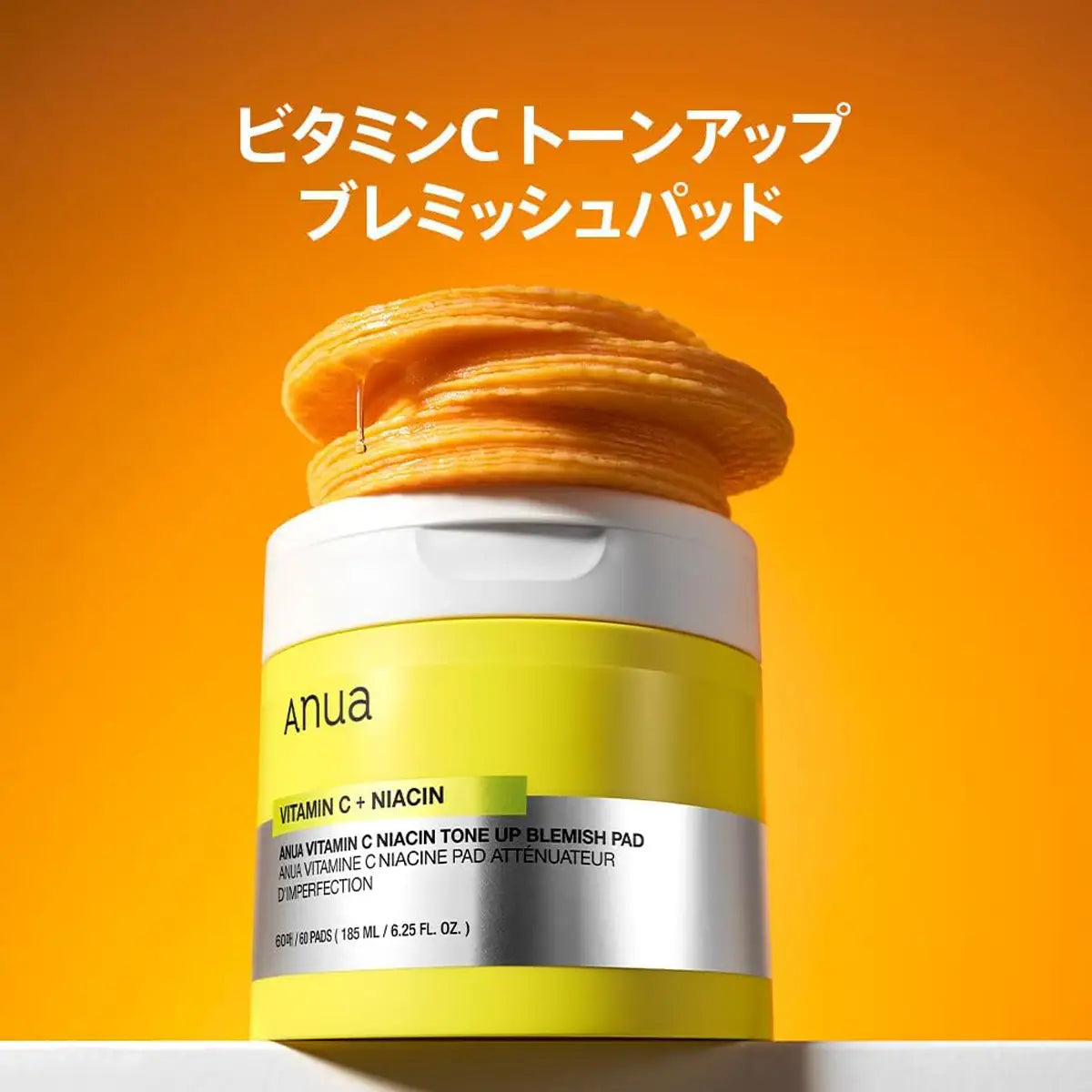 Anua Vitamin C + Niacin skincare pad on an orange background with Japanese text