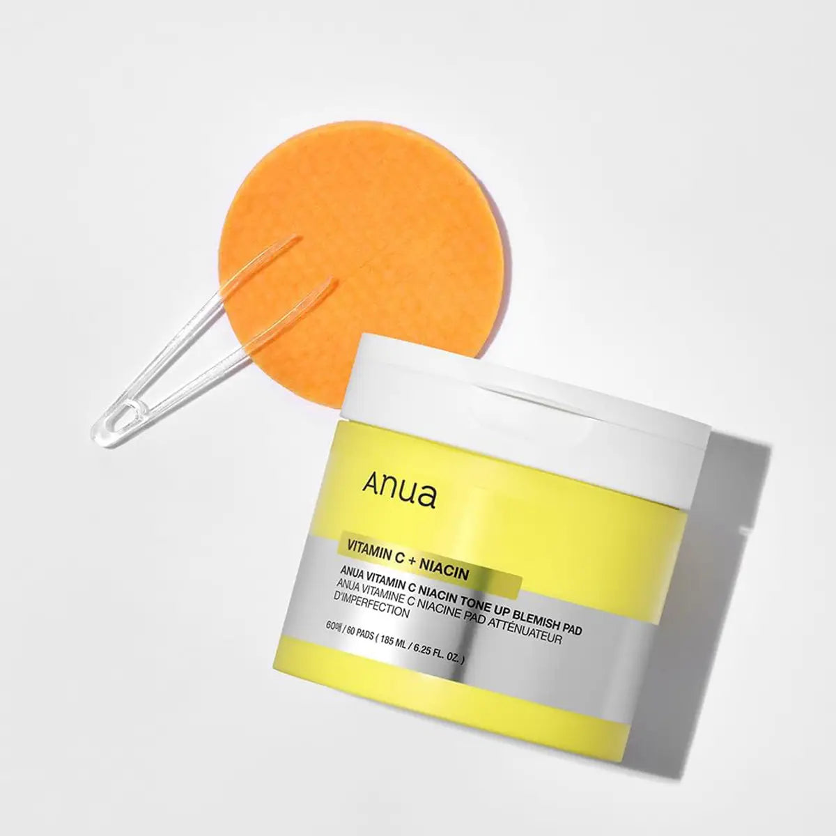 Anua skincare product with a yellow container and orange applicator on a light gray background
