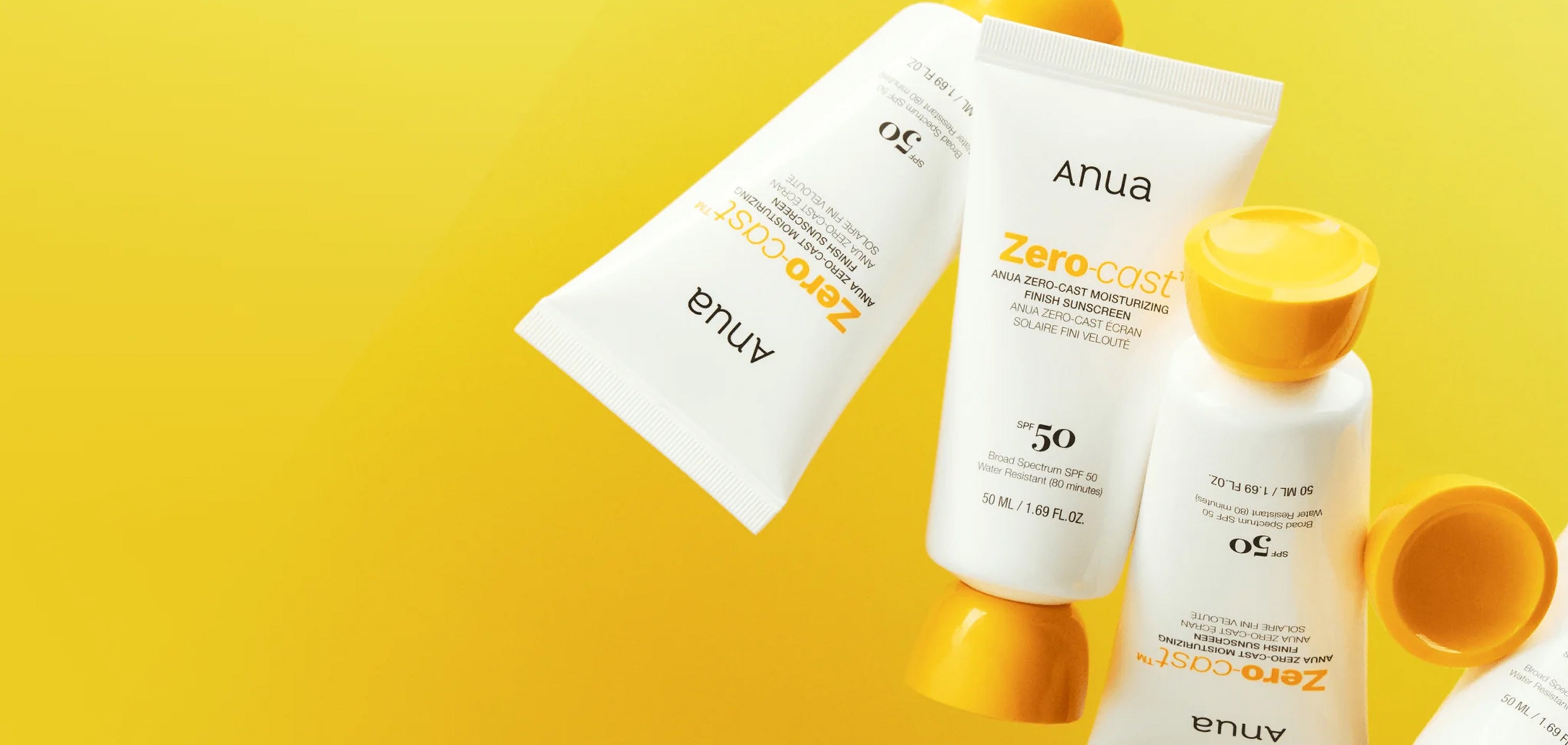 Anua Zero Cast sunscreen bottles and tubes on a yellow background