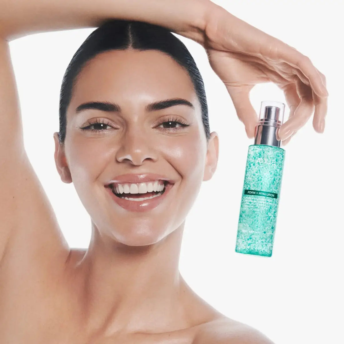 Woman holding a skincare product with a plain background