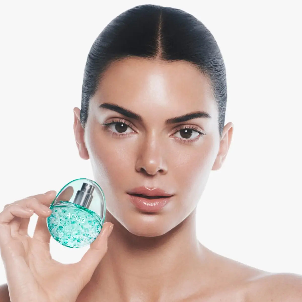 Woman holding a turquoise perfume bottle against a white background