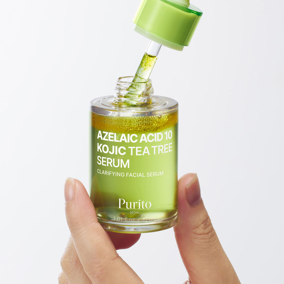 Hand holding a bottle of Purito Azelaic Acid 10 Kojic Tea Tree Serum with a dropper.