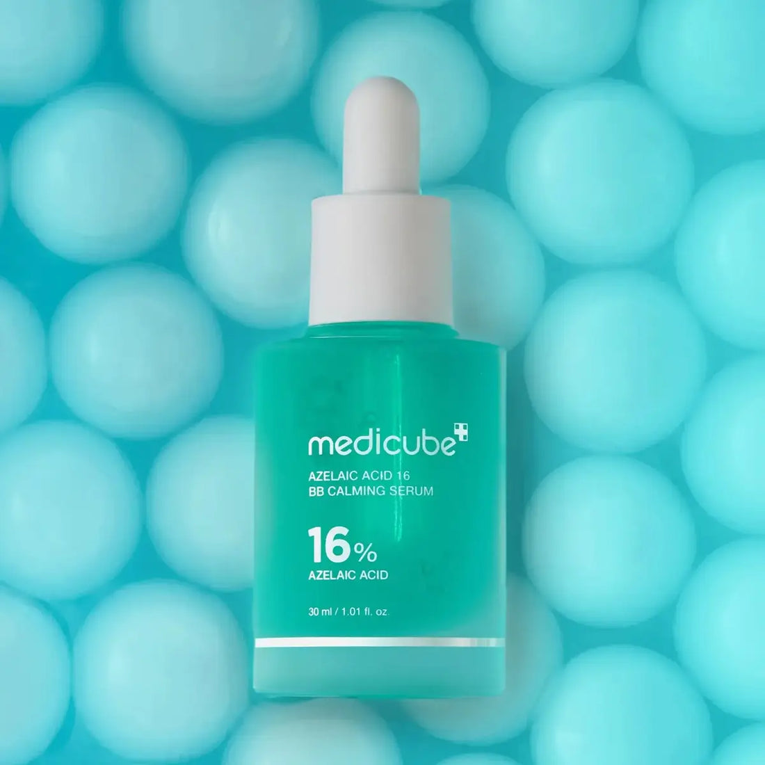 Medicube serum bottle on a blue background with blurred spheres