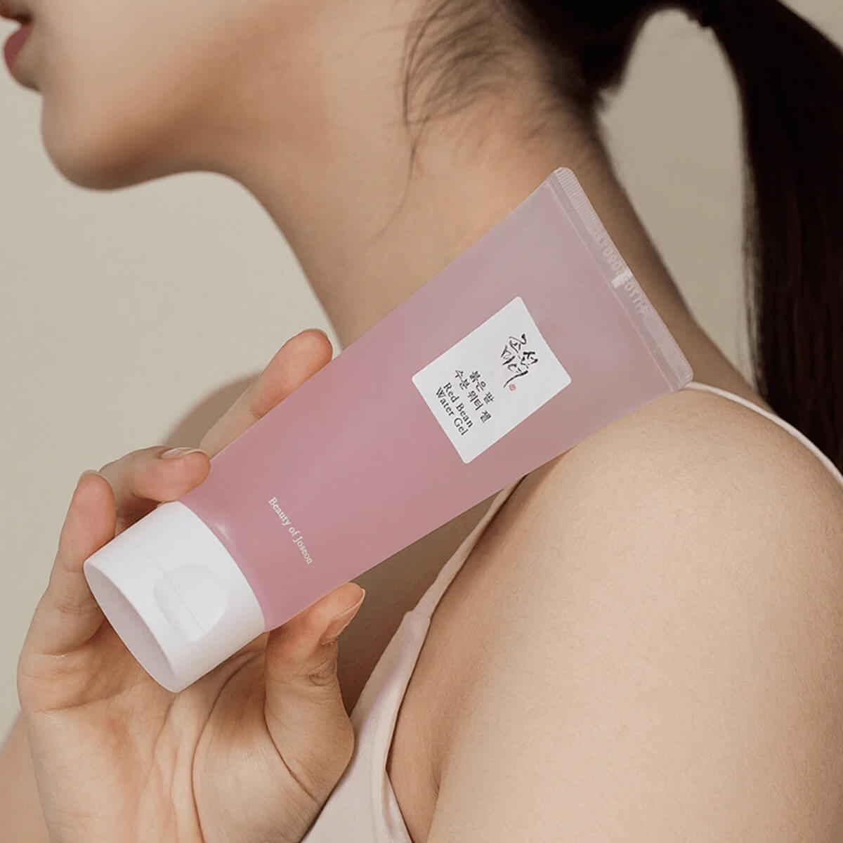 Person holding a pink skincare product with a neutral background