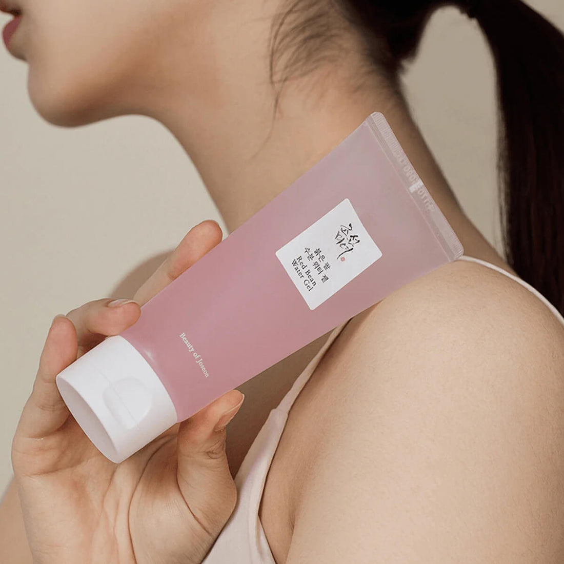 Person holding a pink skincare product with a neutral background