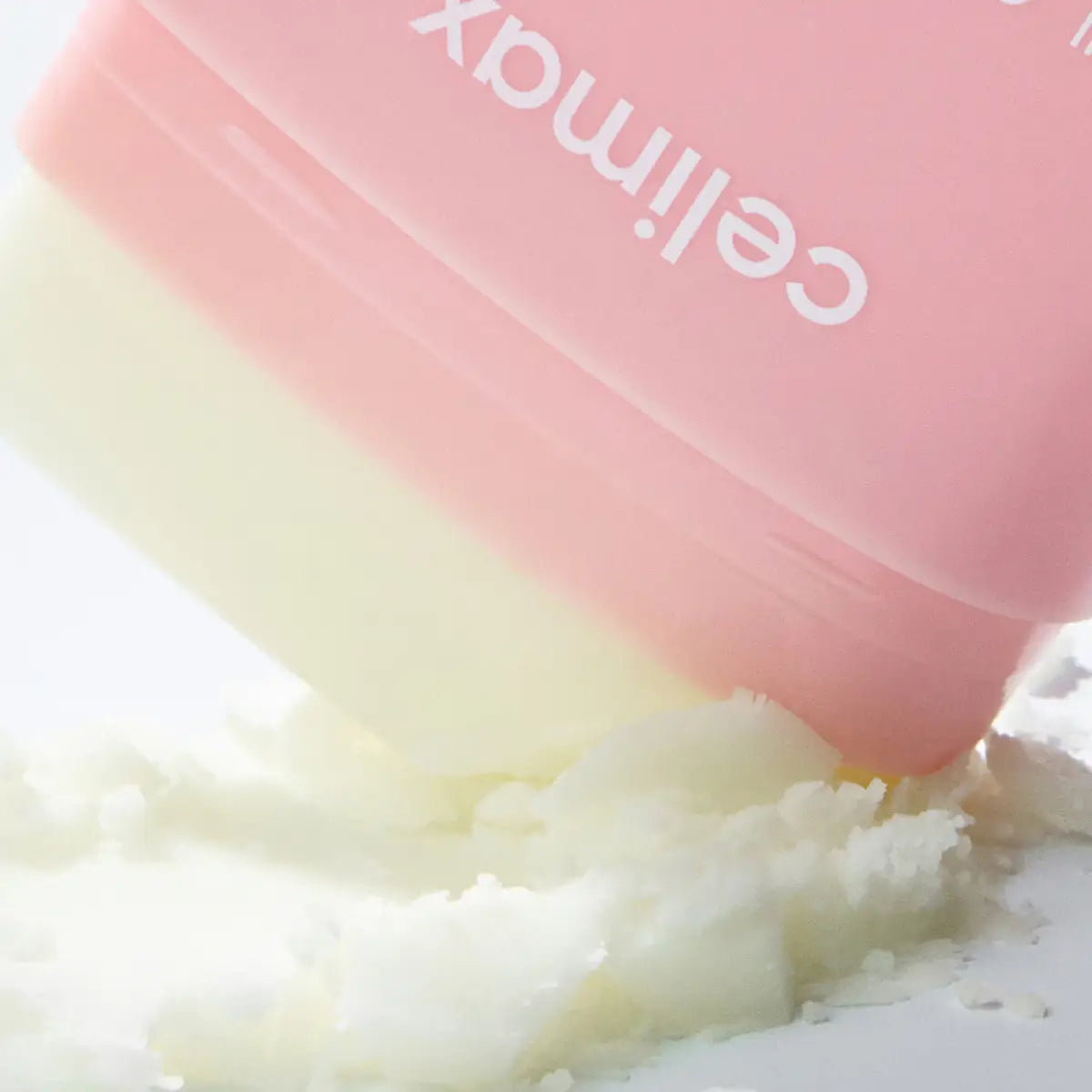 Pink container with a white substance, likely a skincare product, on a light background.