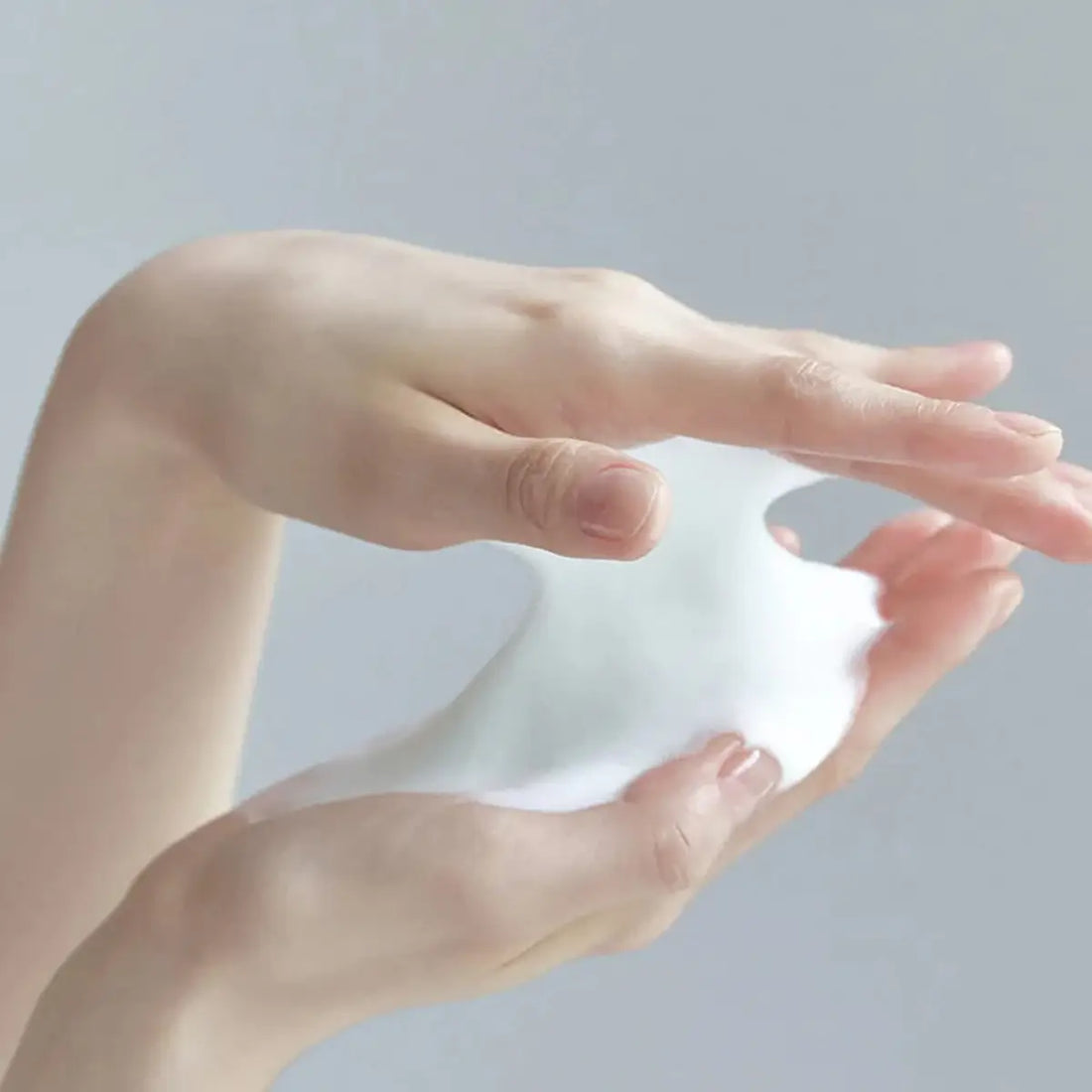 Hands holding a small piece of white paper against a light gray background