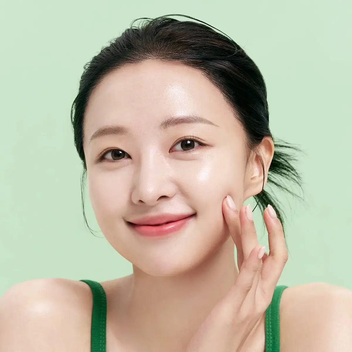 Woman applying toner to her face against a green background