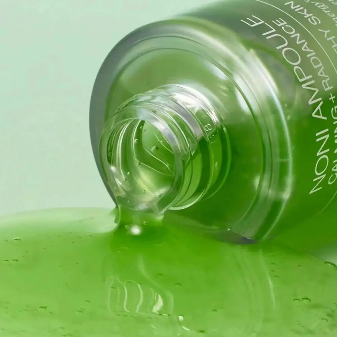 Green bottle of skincare product with visible brand name on a green background