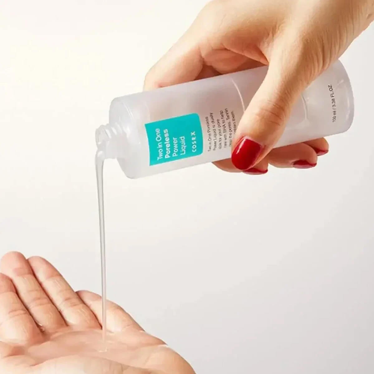 Hand holding a bottle of clear liquid over another hand on a white background