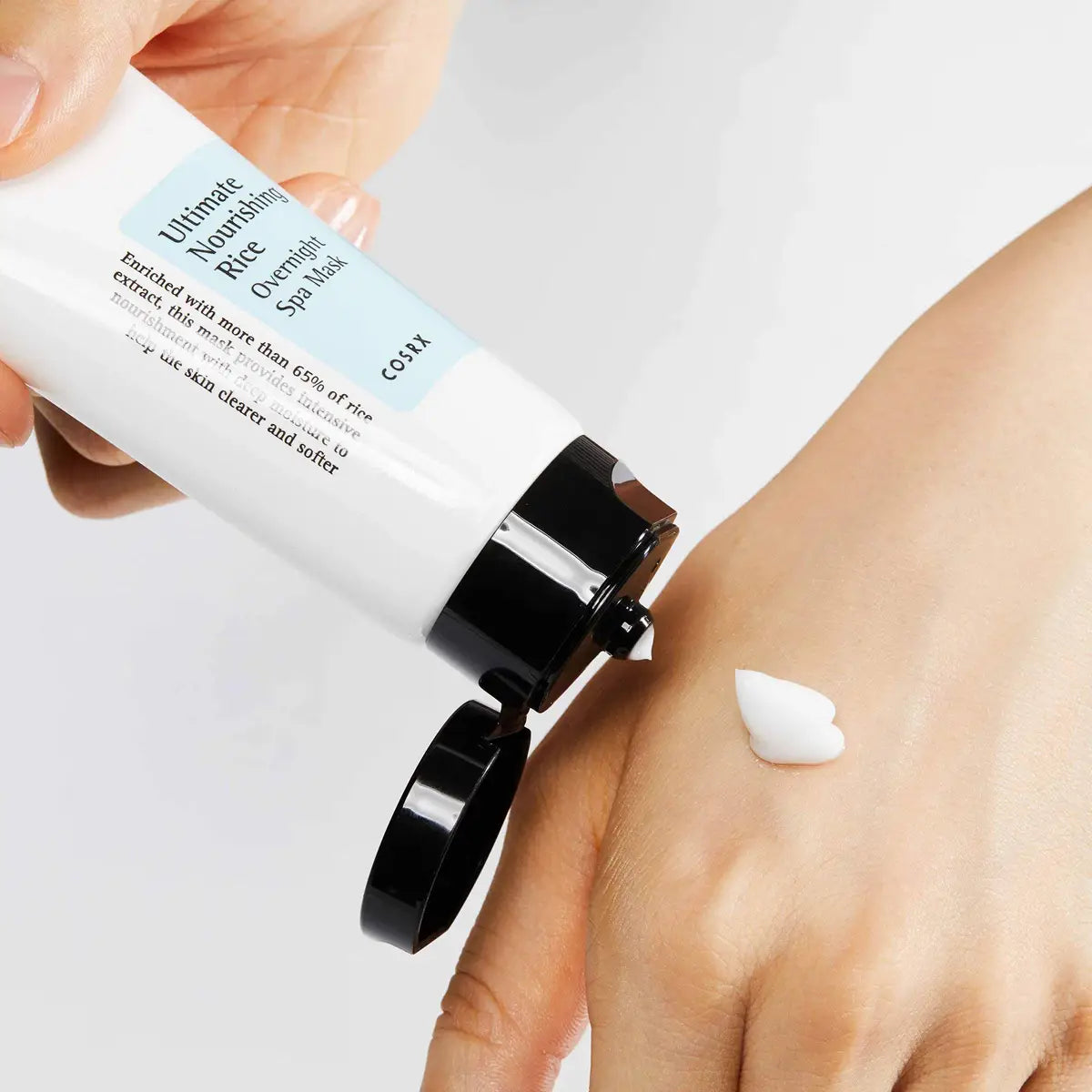 Hand applying skincare product to wrist with visible brand name