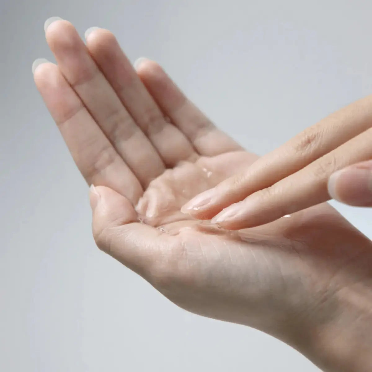 Close-up of a hand with clear skin on a light gray background