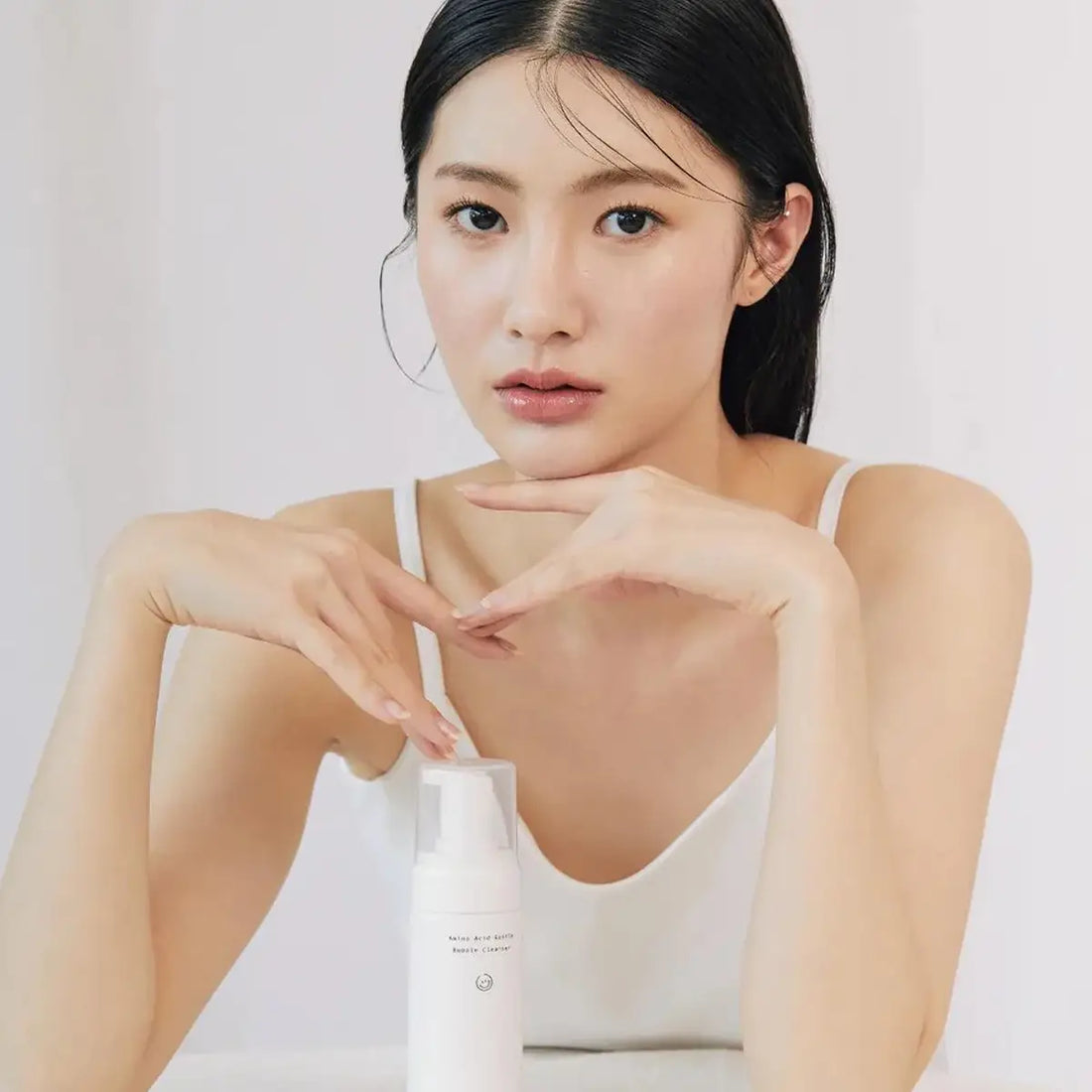 Woman holding a skincare product against a plain background