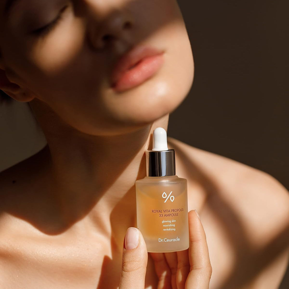 Person holding a skincare serum bottle with a blurred background