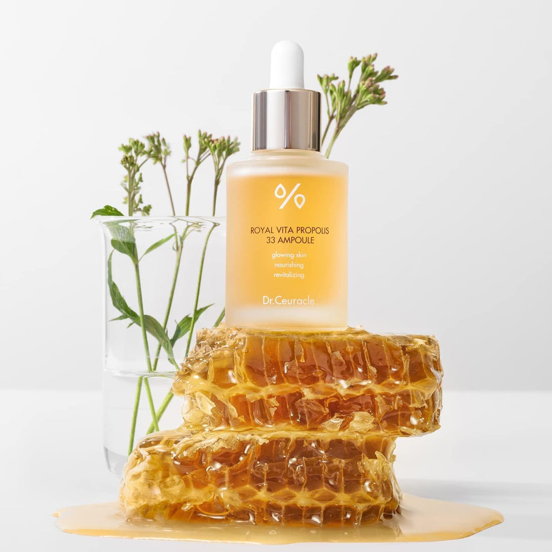 Skincare ampoule bottle on a honeycomb with plants in the background