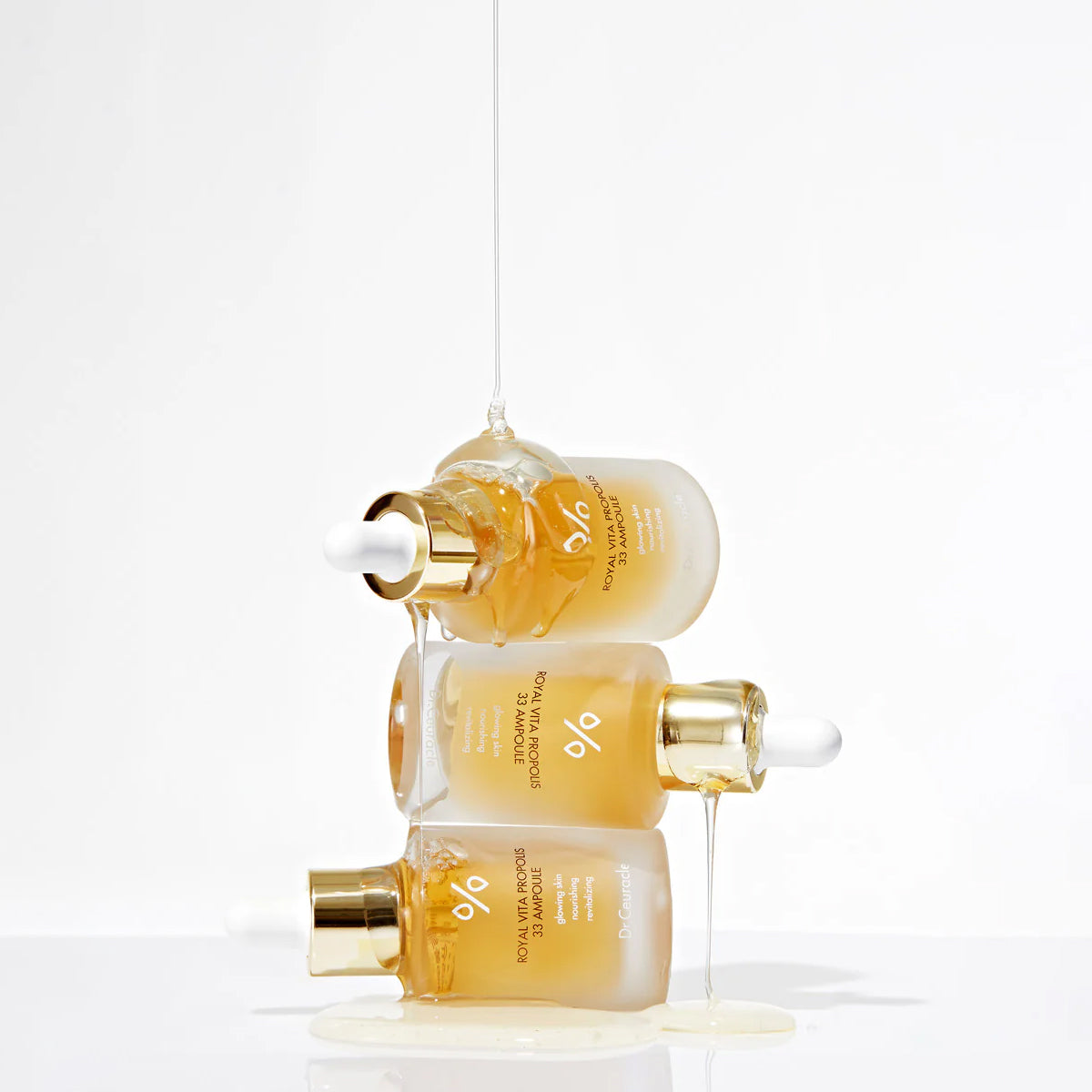 Two skincare serum bottles with gold caps on a white background