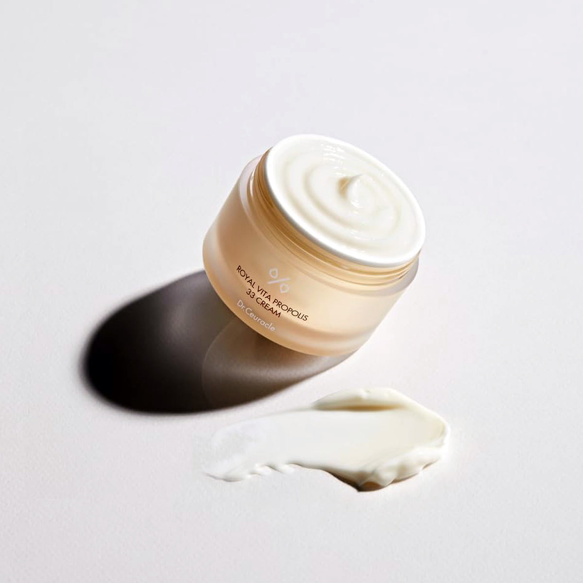 Jar of cream with a swatch on a light gray background