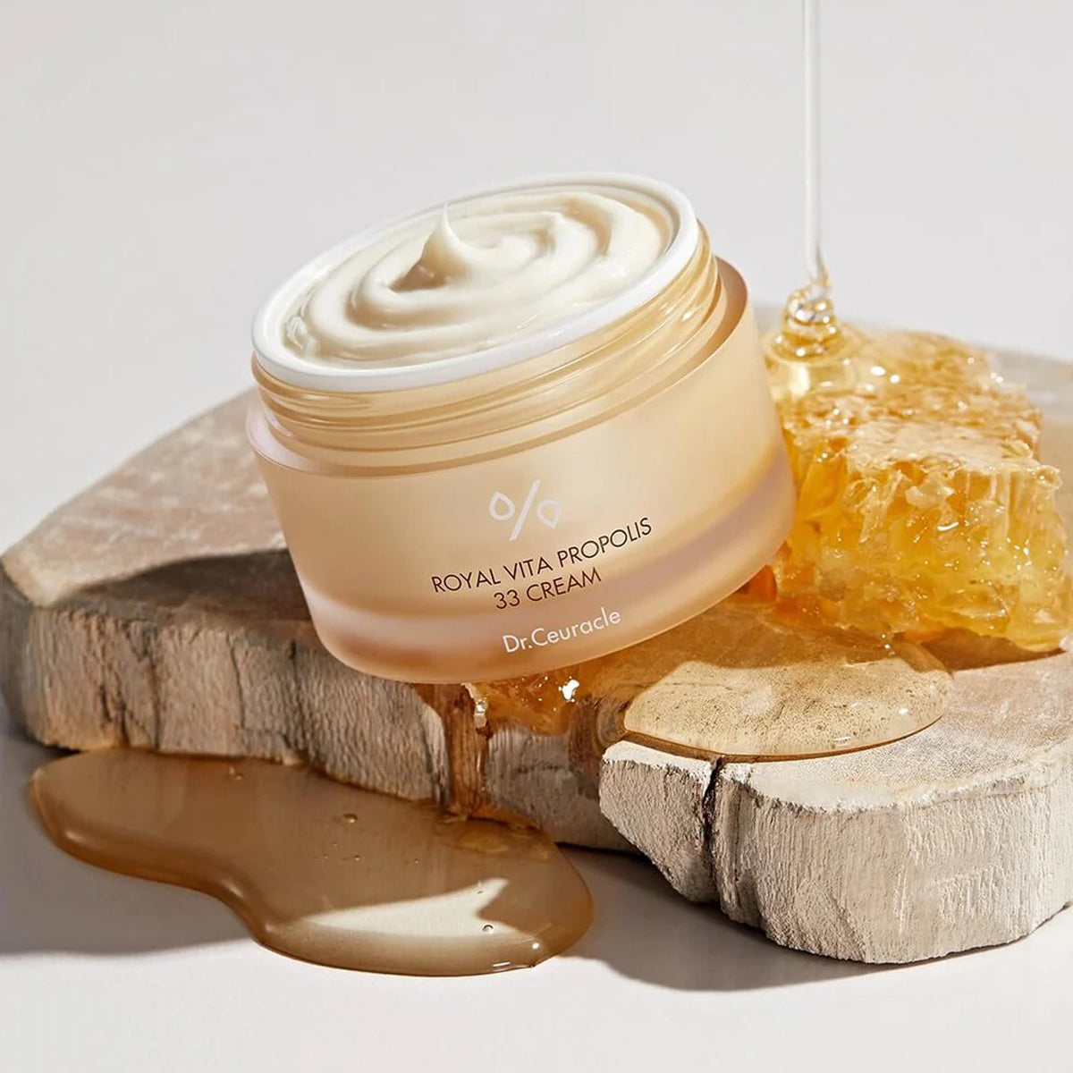 Cream jar with honey on a wooden block against a light background