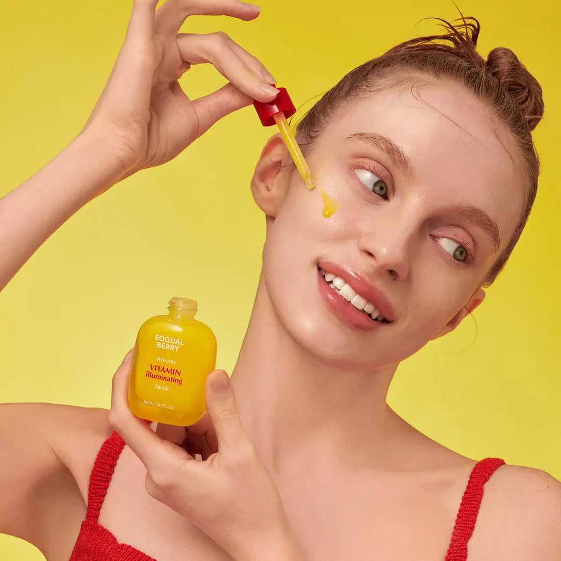 Woman applying Eqqualberry Vitamin Illuminating Serum on a yellow background