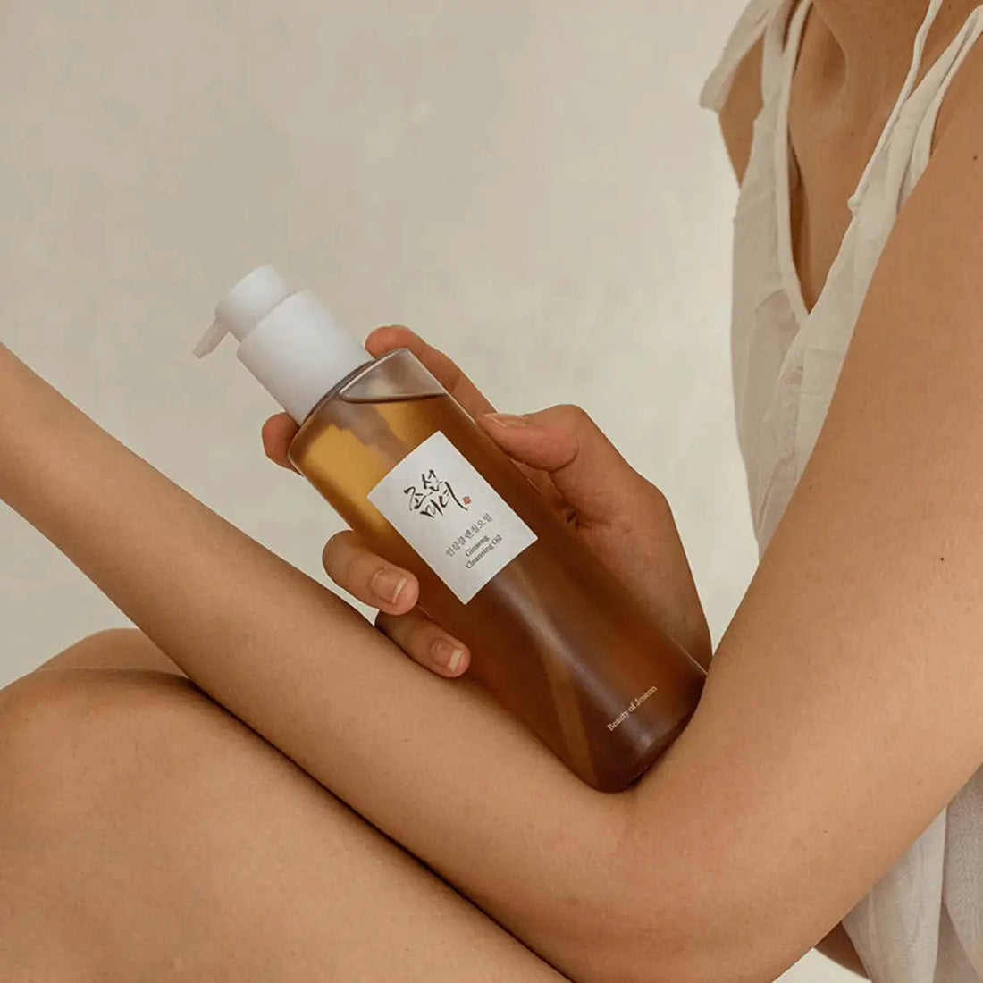 Person holding a brown bottle with a white pump against a neutral background