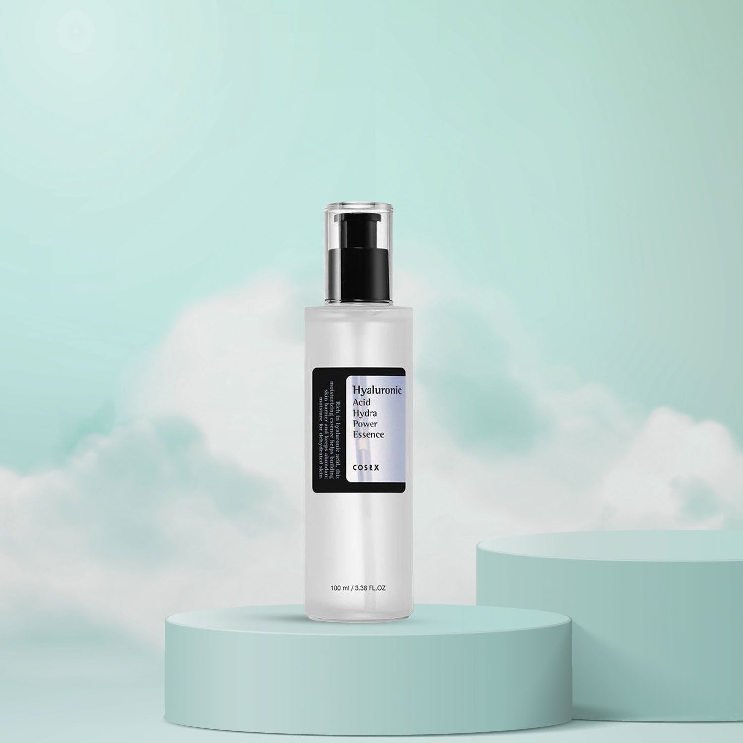 A white, pump bottle of COSRX Hyaluronic Acid Hydra Power Essence, presented on a teal pedestal with a cloudy background.