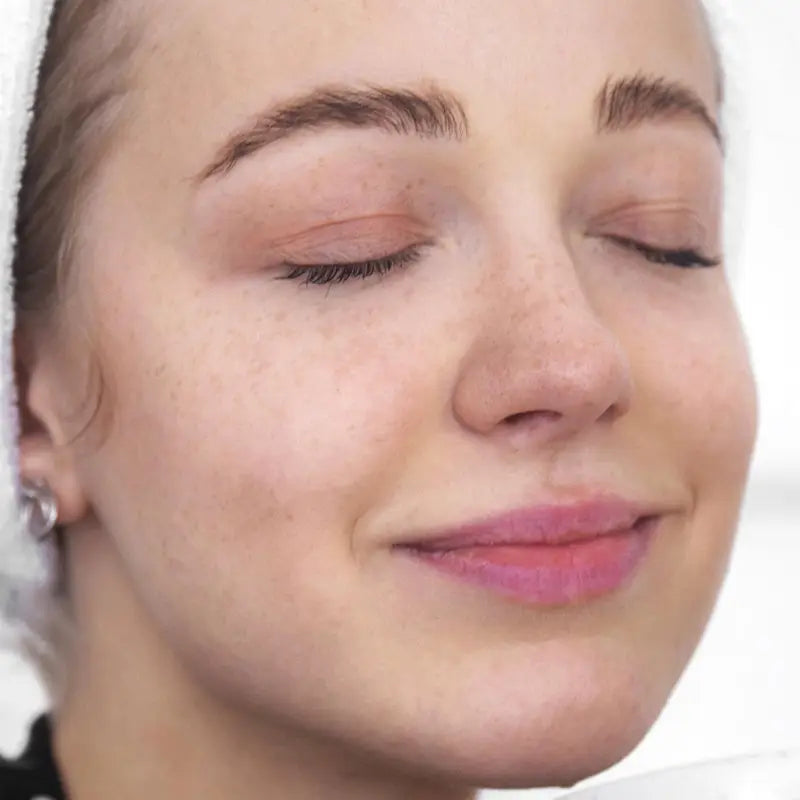 Close-up of a woman's face with closed eyes and pink lipstick.