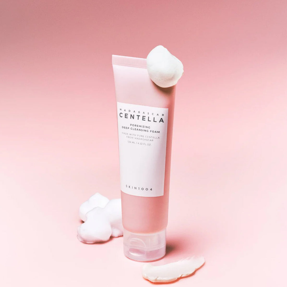 Skincare foam tube with cotton pads on a pink background