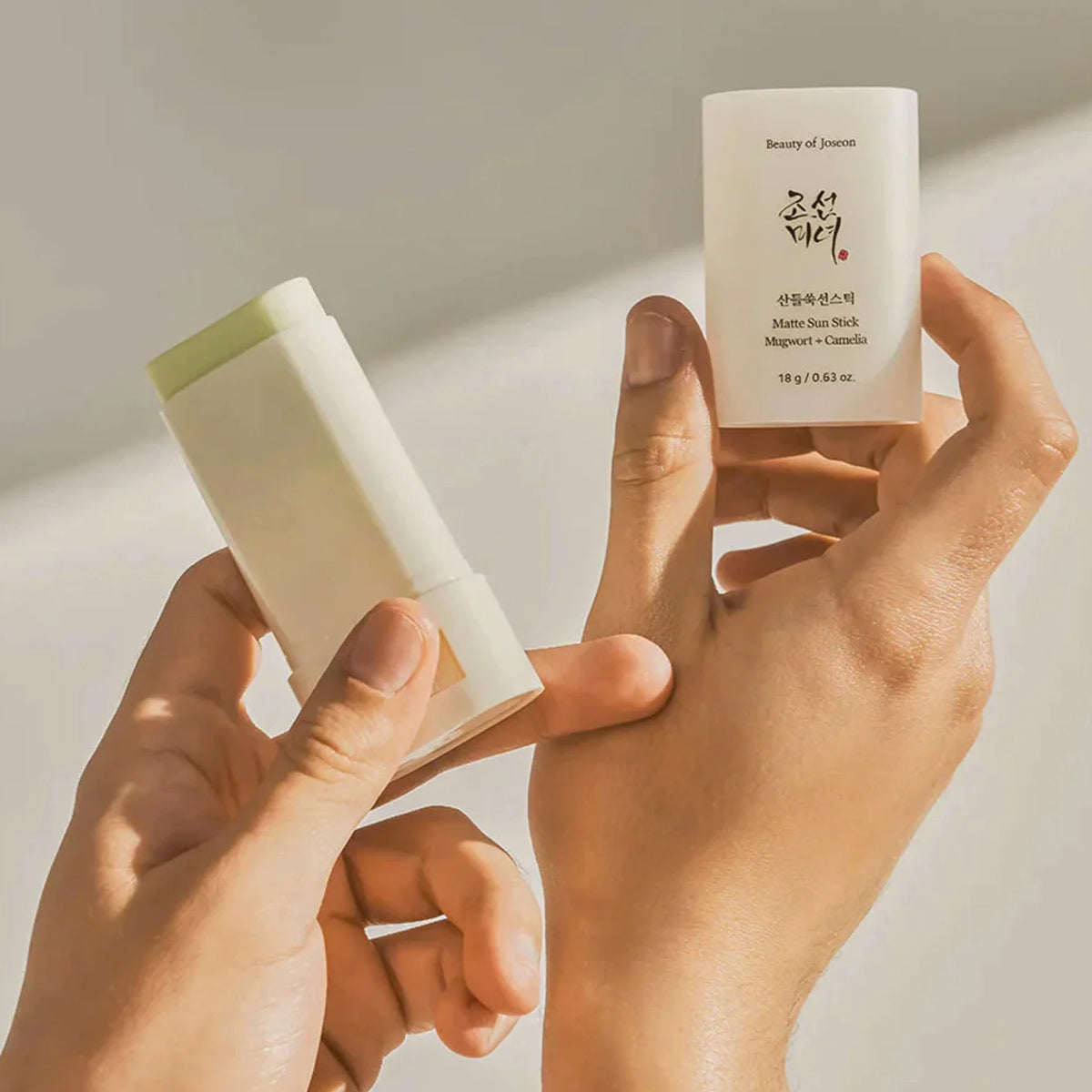 Two skincare products held by hands against a neutral background