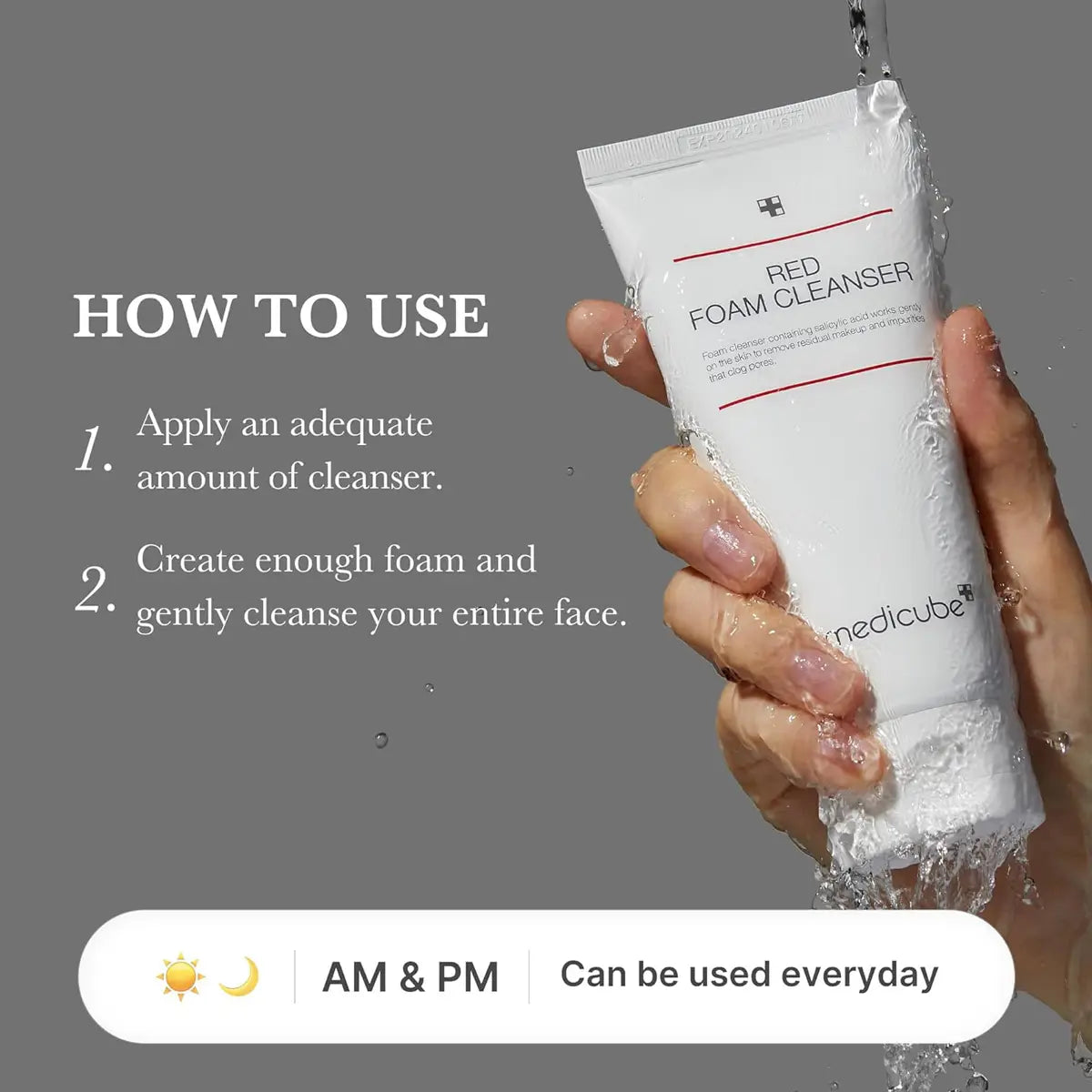 Hand holding a tube of medicube Red Foam Cleanser with usage instructions on a gray background