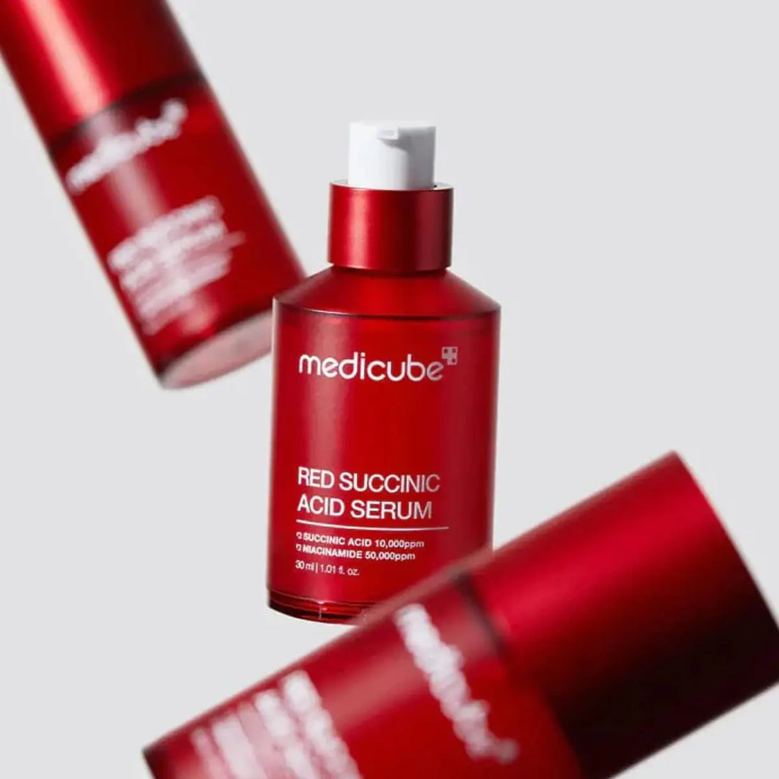 Red bottle of Medicube Red Succinic Acid Serum with a white cap on a light gray background.