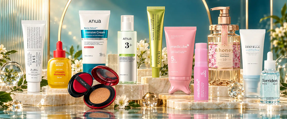 A curated collection of cosmetic products arranged on a reflective marble surface with decorative gold arches and white flowers. Visible brands include Anua, medicube, eqqualberry and Torriden, alongside other skincare and makeup items in white, pink, green, yellow, and blue packaging.