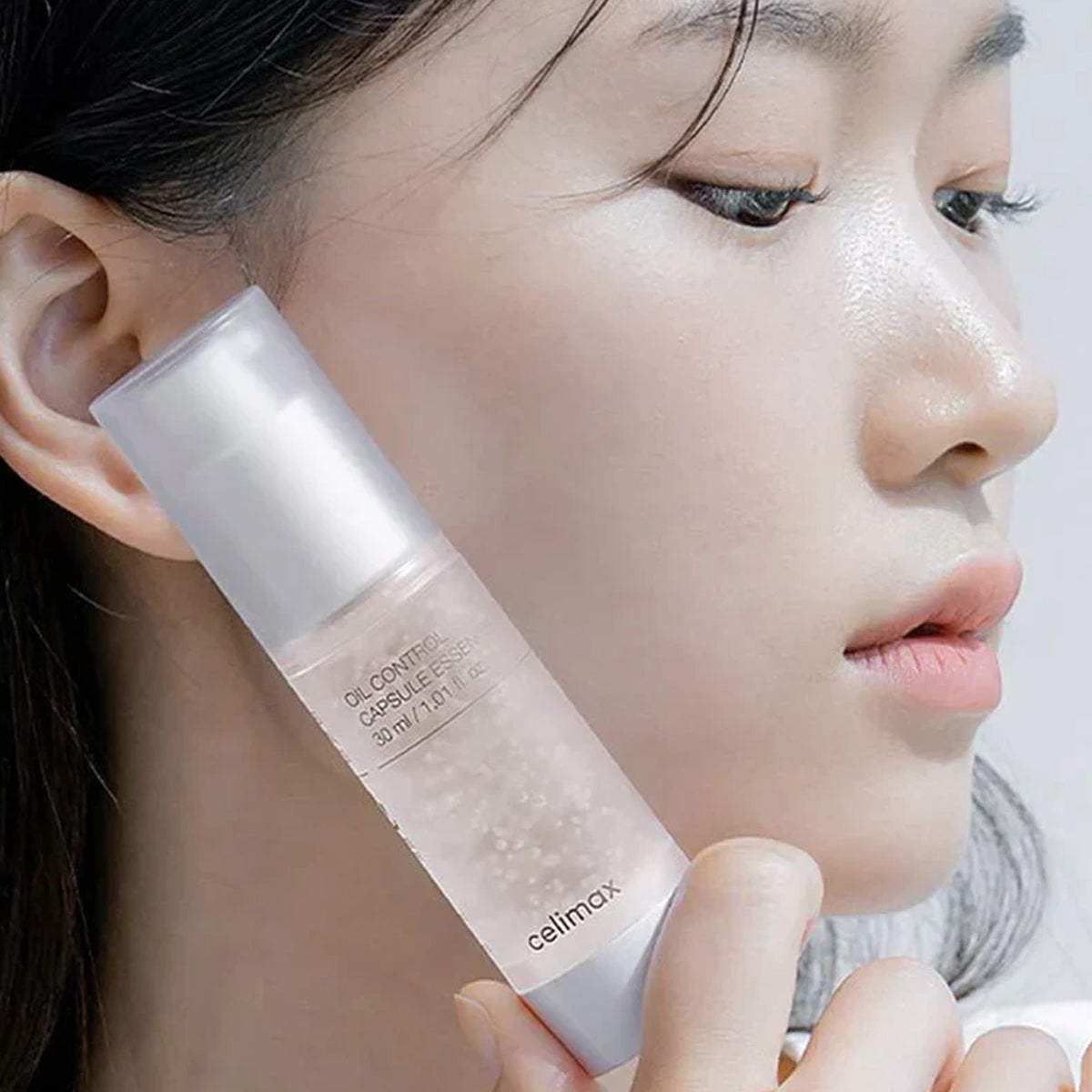 Woman holding a skincare product close to her face