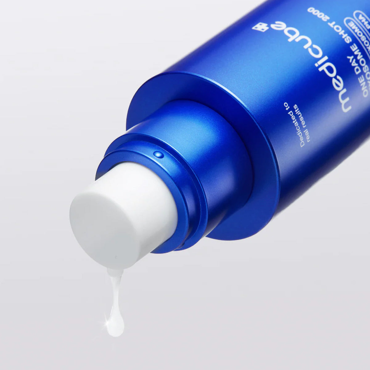 Blue skincare bottle with white cream being squeezed out on a light gray background