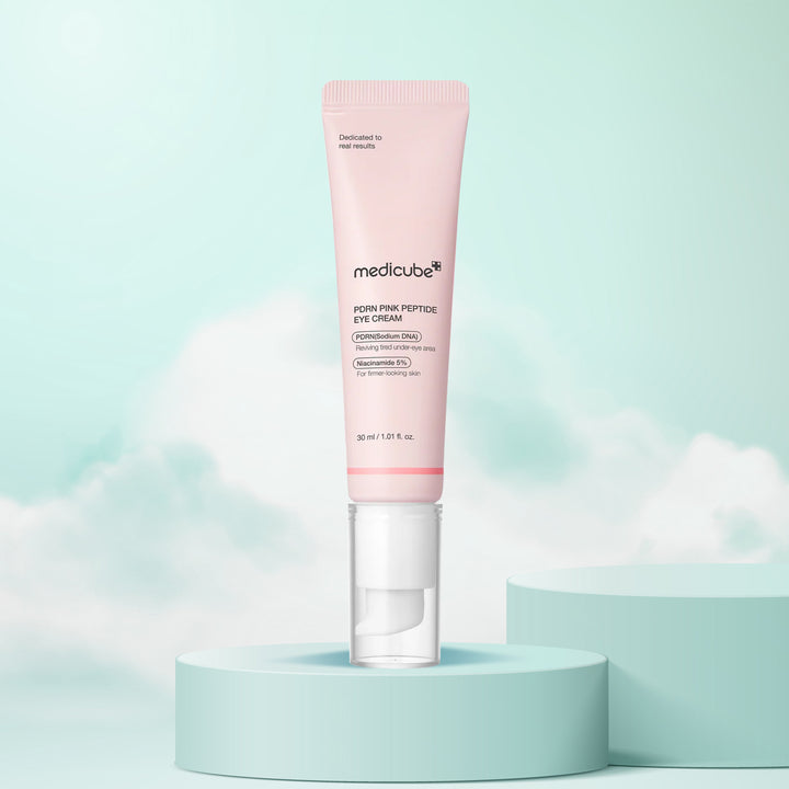 Pink eye cream bottle with 'medicube' branding on a light blue background