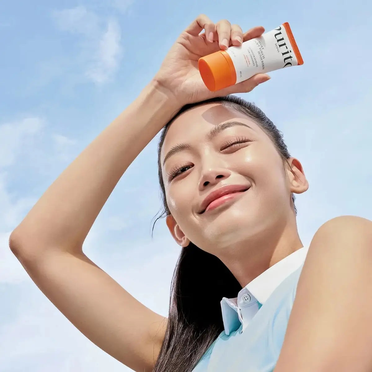 Woman applying sunscreen with a clear blue sky background