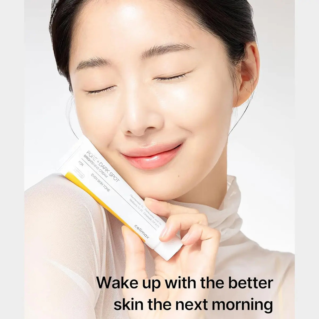 Woman holding aCelimax Pore+Dark Spot Brightening Cream with text 'Wake up with the better skin the next morning' on a light background