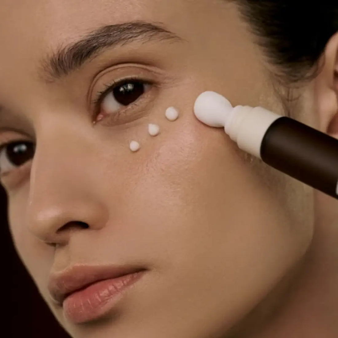 Person applying eye cream to their face