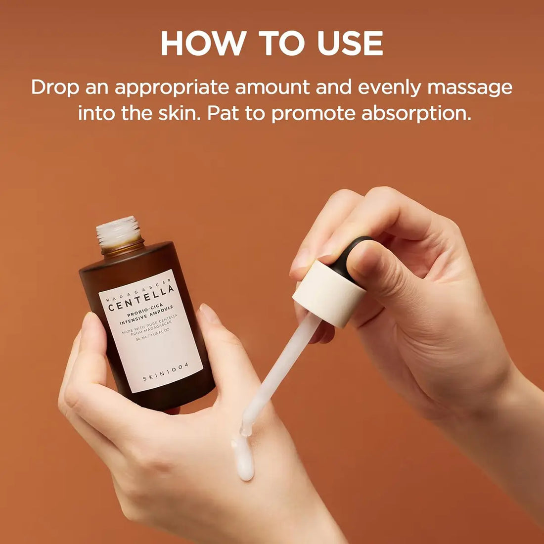 Hand holding a dropper with skincare product and bottle, against a brown background